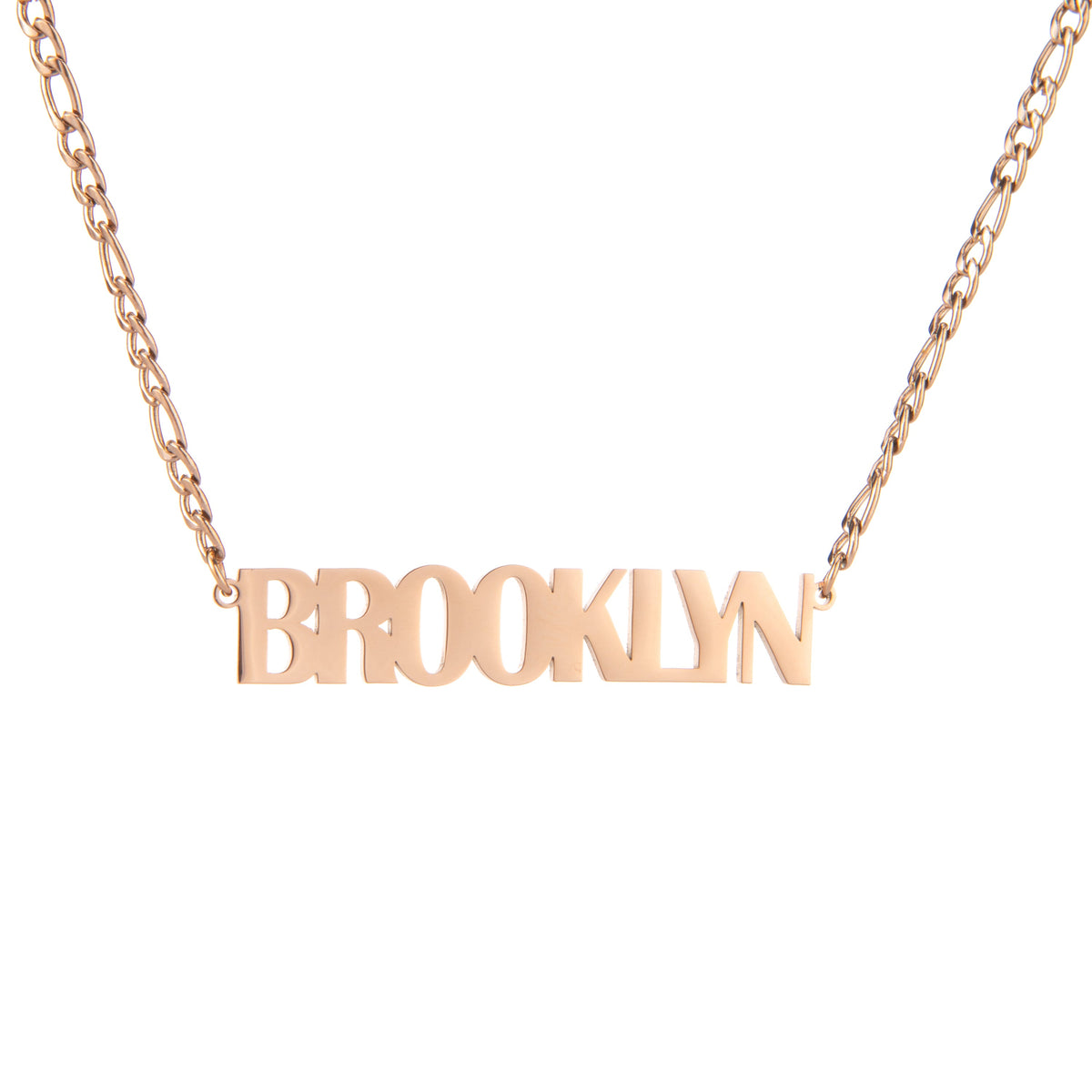 A rose gold-colored necklace with the name 'BROOKLYN' written in bold, all-capital letters.