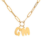 A gold-plated necklace with a single initial 'G' charm attached to a paper clip chain.